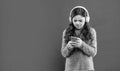 busy teen girl in sweater in headphones for listening music texting in phone, copy space, technology