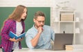 busy teen girl and teacher man in high school with workbook and pc at blackboard, education online
