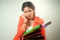 Busy Asian business woman with a lot of folders and colorful papers on background.