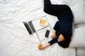 Busy and tired businesswoman eating bread for breakfast in bed at home and working to deliver financial statements to a boss. Royalty Free Stock Photo