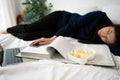 Busy and tired businesswoman eating bread for breakfast in bed at home and working to deliver financial statements to a boss. Royalty Free Stock Photo