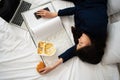 Busy and tired businesswoman eating bread for breakfast in bed at home and working to deliver financial statements to a boss. Royalty Free Stock Photo