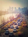 Busy traffic on highway and city streets creating high pollution and smog. Urban sunset view across Seine river to La Defense