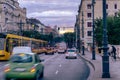 Busy urban street at dusk featuring cars and trams traveling in opposite directions