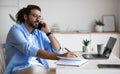 Busy Western Entrepreneur Talking On Mobile Phone And Taking Notes In Office Royalty Free Stock Photo