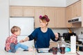 Busy white Caucasian young woman mother housewife with hair-curlers in her hair cooking preparing dinner meal in kitchen Royalty Free Stock Photo