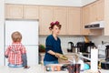 Busy white Caucasian young woman mother housewife with hair-curlers in her hair cooking preparing dinner meal in kitchen Royalty Free Stock Photo