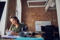 Busy woman interior designer making notes in her notebook while working on new creative project, sitting at the table in Royalty Free Stock Photo