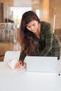 Busy woman taking notes while using laptop