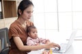 Busy woman trying to work while babysitting newborn baby daughte. Young beautiful Asian mother holding little baby on lap while
