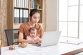 Busy woman trying to work while babysitting newborn baby daughte. Young beautiful Asian mother holding little baby on lap while