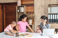 Busy woman trying to work while babysitting three kids.  Young Asian mother on a call with three children playing around her . Royalty Free Stock Photo