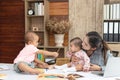 Busy woman trying to work while babysitting two kids.  Young Asian mother talking and playing with two children playing around her Royalty Free Stock Photo