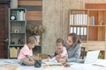 Busy woman trying to work while babysitting two kids.  Young Asian mother talking and playing with two children playing around her Royalty Free Stock Photo