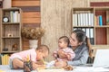 Busy woman trying to work while babysitting two kids.  Young Asian mother talking and playing with two children playing around her Royalty Free Stock Photo