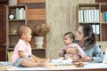 Busy woman trying to work while babysitting two kids.  Young Asian mother talking and playing with two children playing around her Royalty Free Stock Photo