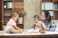 Busy woman trying to work while babysitting two kids.  Young Asian mother talking and playing with two children playing around her Royalty Free Stock Photo