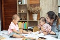 Busy woman trying to work while babysitting two kids.  Young Asian mother talking and playing with two children playing around her Royalty Free Stock Photo