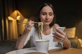 Busy woman uses a smartphone while having dinner in the bedroom. A student eats fast food while working on a new project Royalty Free Stock Photo