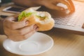 Busy woman worker eating junk food burger while working on laptop in office Royalty Free Stock Photo