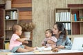 Busy woman trying to work while babysitting two kids.  Young Asian mother talking and playing with two children playing around her Royalty Free Stock Photo