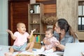 Busy woman trying to work while babysitting two kids.  Young Asian mother talking and playing with two children playing around her Royalty Free Stock Photo