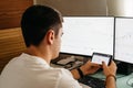 Successful young trader in casual wear working with charts and market reports at home