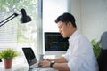 Busy young asian modern man in formalwear working using computers while sitting in the office Royalty Free Stock Photo