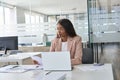 Busy young business woman executive reading papers working on laptop in office. Royalty Free Stock Photo