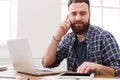 Busy young businessman using digital tablet and talking on mobile in office Royalty Free Stock Photo