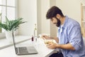 Busy young man eating takeaway food during lunch break at home or in the office Royalty Free Stock Photo