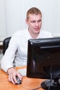 Busy young man in white shirt sitting at pc computer