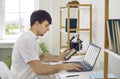 Young man working in his home office, sitting at desk, and using laptop and mobile phone Royalty Free Stock Photo