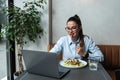 Busy young professional business woman wearing suit using laptop computer sitting in cafe restaurant. Hungry manager remote