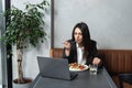 Busy young professional business woman wearing suit using laptop computer sitting in cafe restaurant. Hungry manager remote