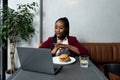 Busy young professional business woman wearing suit using laptop computer sitting in cafe restaurant. Hungry manager remote