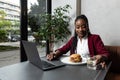 Busy young professional business woman wearing suit using laptop computer sitting in cafe restaurant. Hungry manager remote