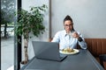 Busy young professional business woman wearing suit using laptop computer sitting in cafe restaurant. Hungry manager remote