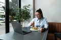 Busy young professional business woman wearing suit using laptop computer sitting in cafe restaurant. Hungry manager remote
