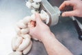 Butcher in butchery filling sausages