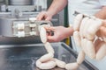 Butcher in butchery filling sausages