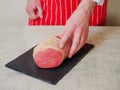 Butcher checking out eye of round roast of beef on a black slate board and simple white table cloth, Concept meat industry, Royalty Free Stock Photo