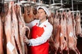 Butcher checking raw lamb carcasses hanging in cold storage