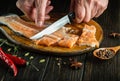 A butcher cuts raw salmon fish on a kitchen cutting board with a knife. Delicious lunch of red fish for a restaurant or hotel by Royalty Free Stock Photo