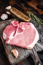 Butcher cutting board with Raw T-bone pork chop meat steak. Wooden background. Top view