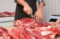 Butcher cutting fresh raw meat on counter in shop Royalty Free Stock Photo