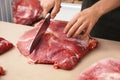 Butcher cutting fresh raw meat on counter in shop