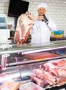 Butcher holding slab of raw beef ribs at counter Royalty Free Stock Photo