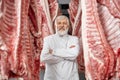 Butcher posing, standing between rows of pork carcasses. Royalty Free Stock Photo
