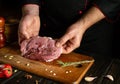 A butcher is preparing a beef steak on the kitchen table for barbecue for lunch. Chef hands with a cut piece of raw veal meat Royalty Free Stock Photo